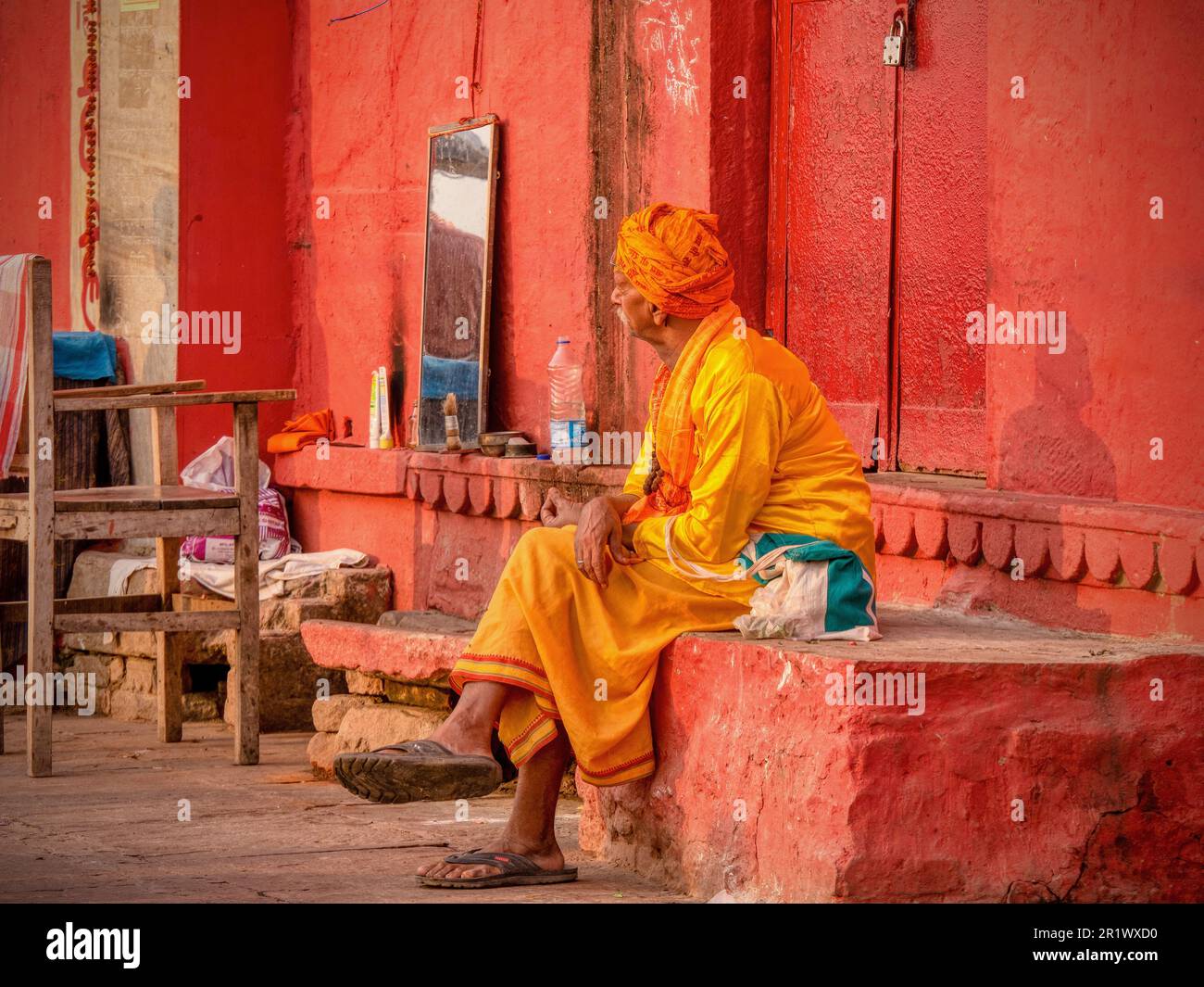Varanasi, Indien - 13. November 2015. Ein indischer Barbier in traditioneller Kleidung wartet in einem provisorischen Außenbereich auf Kunden. Stockfoto