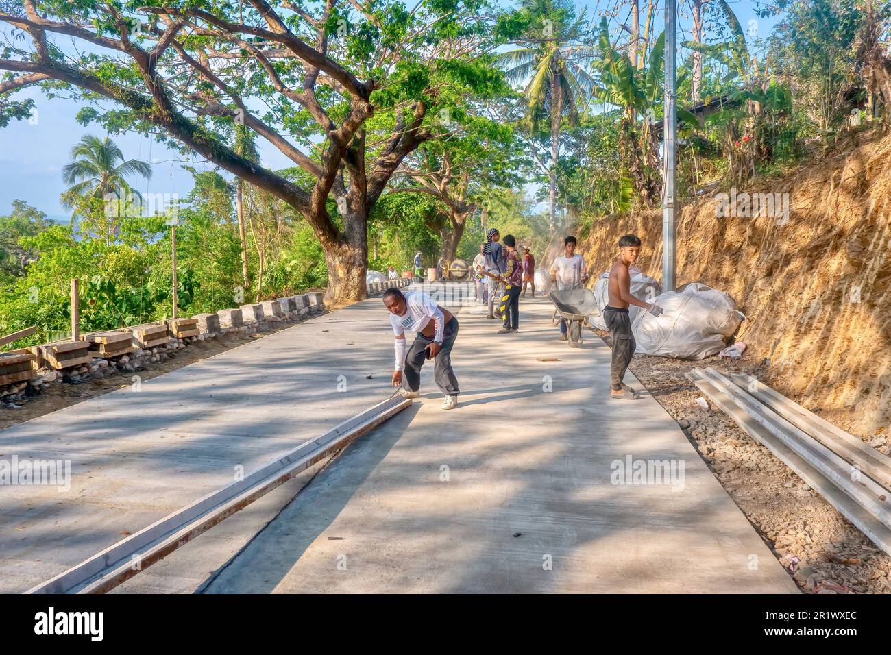 Puerto Galera, Philippinen - 22. April 2023. Eine Gruppe philippinischer Arbeiter, die auf einer Straßenbaustelle in der Nähe des Dorfes Baclayan arbeiten. Stockfoto