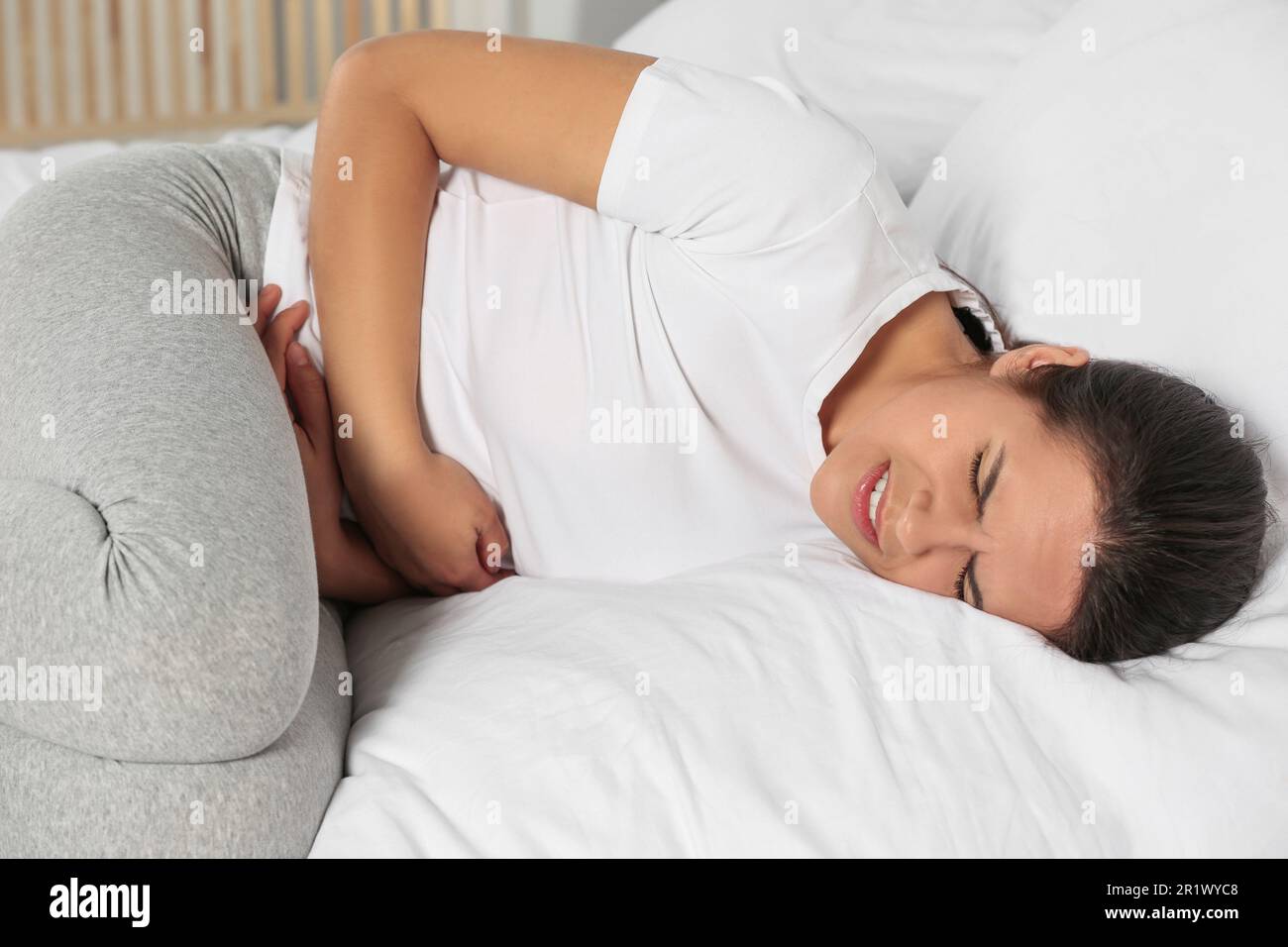Junge Frau mit Zystitis im Bett Stockfoto
