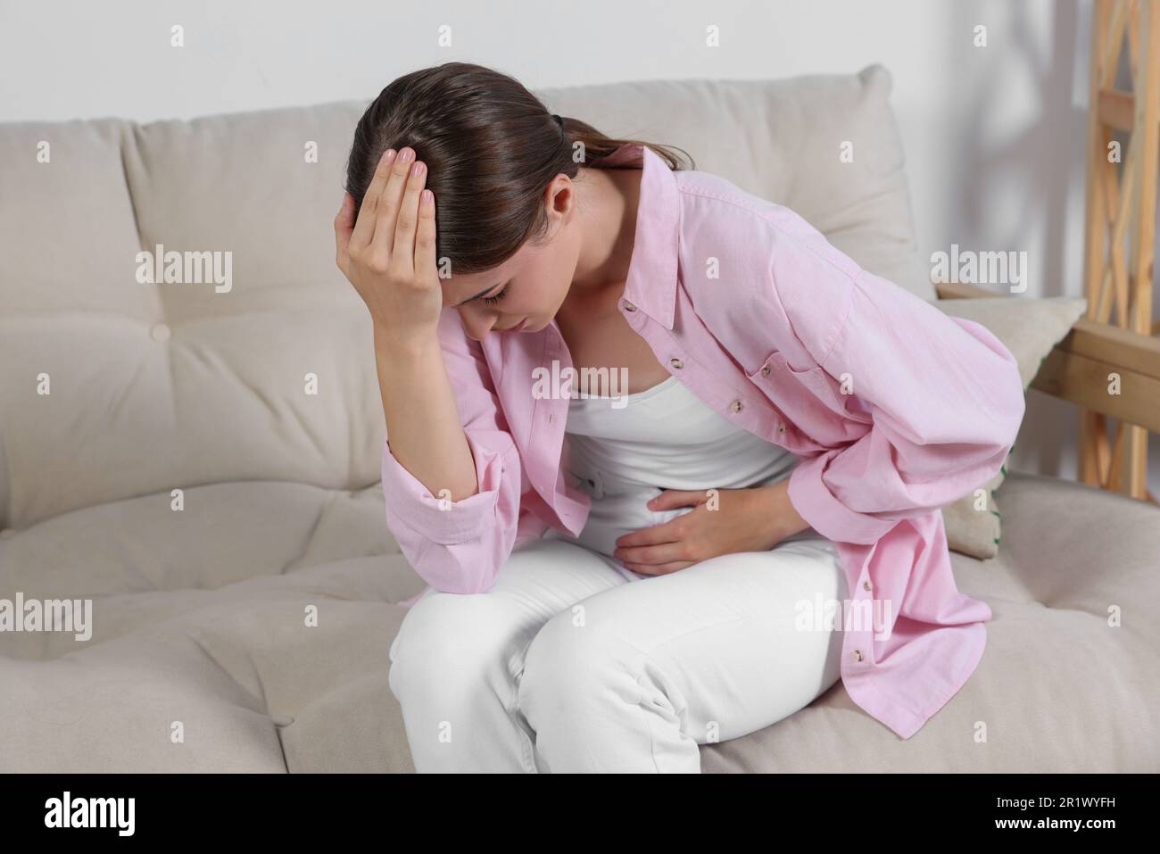 Junge Frau mit Zystitis auf dem Sofa zu Hause Stockfoto