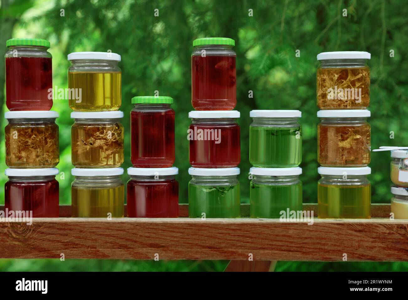 Verschiedene Honigsorten in Gläsern auf Holztisch im Freien Stockfoto
