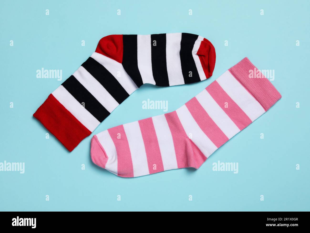 Verschiedene gestreifte Socken auf hellblauem Hintergrund, flach liegend Stockfoto