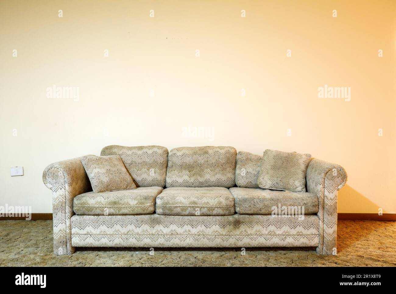 Eine dreckige Couch, die vor einer völlig leeren Wand saß. Dieses Haus wurde seitdem abgerissen. Stockfoto