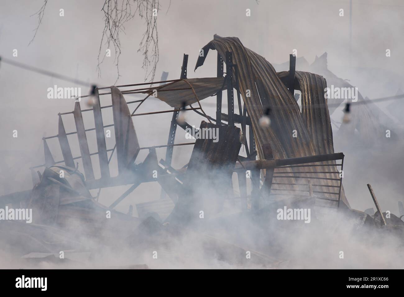 Die Reste eines Gebäudes nach einem Feuer, mit Rauch, der immer noch vom Schwelbrand kommt. Stockfoto