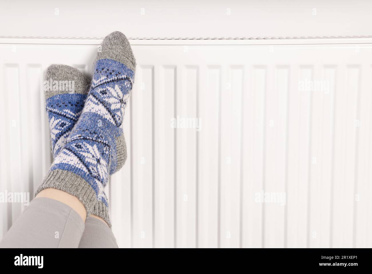 Frau wärmt Füße in der Nähe des Heizkörpers, Nahaufnahme. Platz für Text Stockfoto