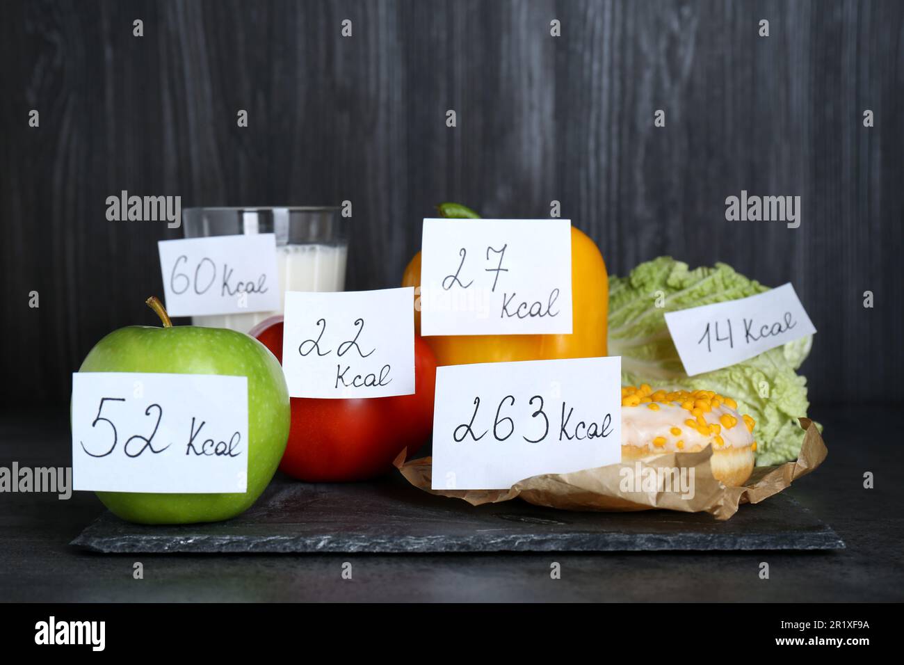 Lebensmittelprodukte mit Heizwert-Tags auf schwarzem Tisch. Gewichtsverlust-Konzept Stockfoto