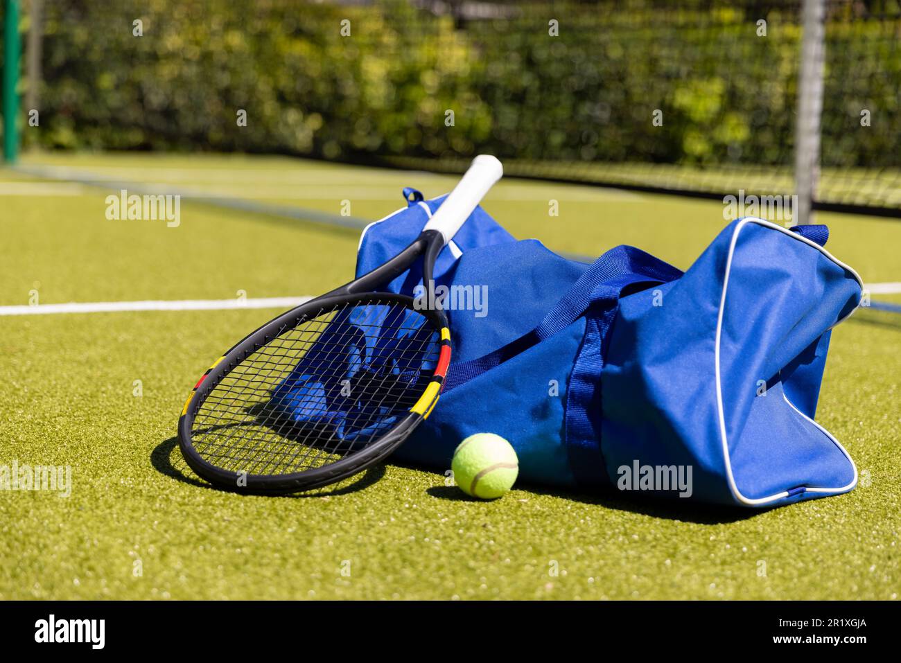 Tennisschläger, Ball und Sporttasche auf einem sonnigen Tennisplatz Stockfoto