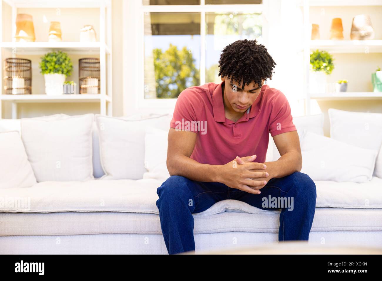 Besorgter, trauriger birassistischer Mann, der auf dem Sofa im Wohnzimmer sitzt und denkt, Kopierraum Stockfoto