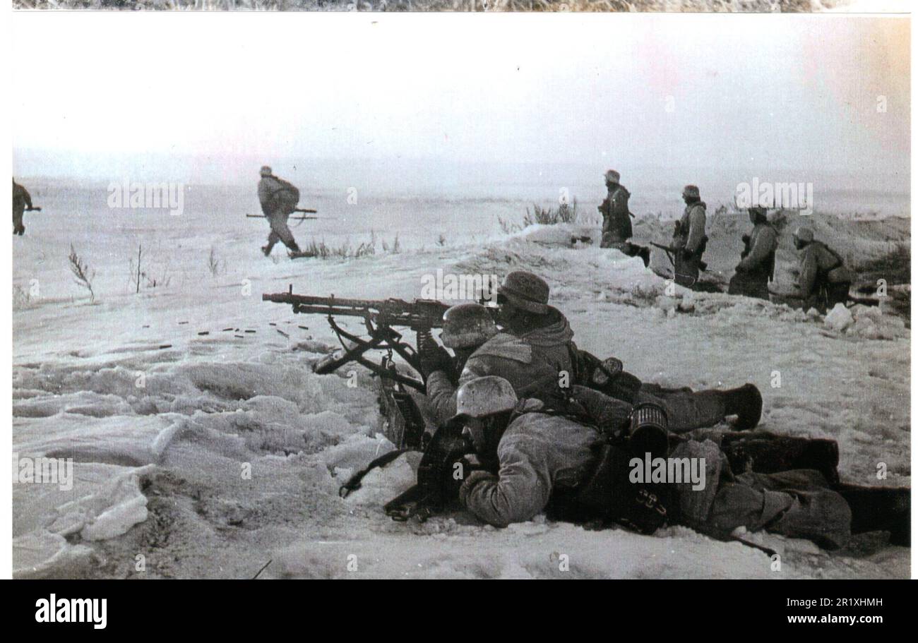 World war Two B&W Foto Deutsche Soldaten in Snow Camo gehen mit dem Deckungsfeuer eines Heavy MG Teams vor Stockfoto