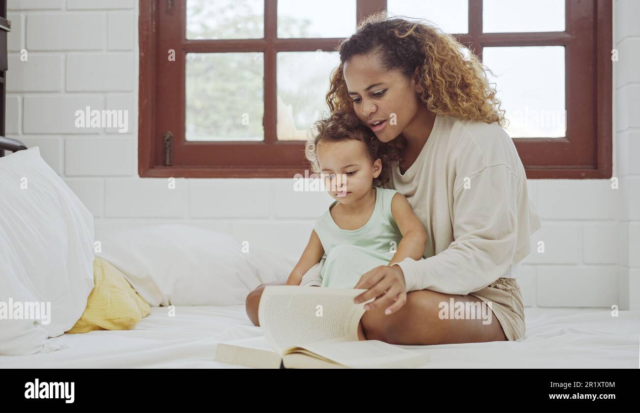 Junge Mutter liest ein Buch mit ihrer Tochter. Stockfoto