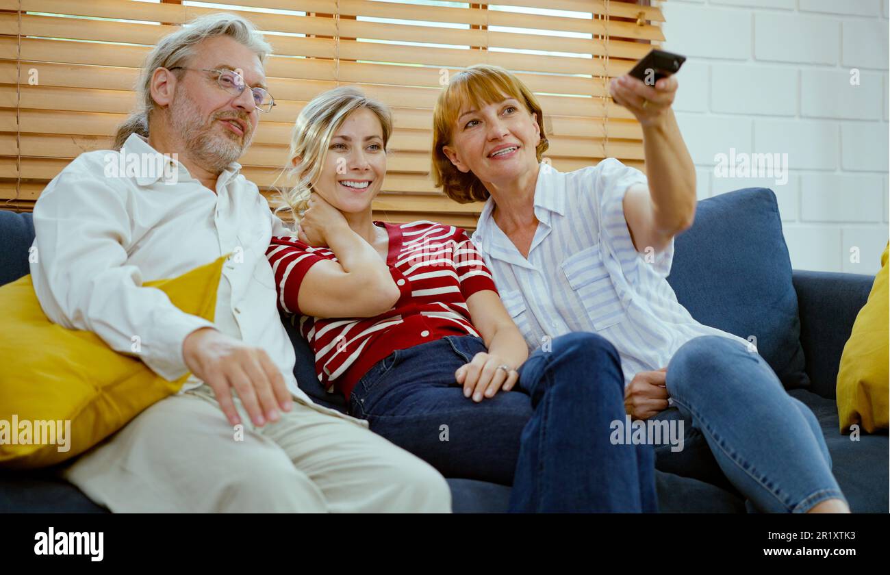 Glückliche Familie, die auf dem Sofa sitzt und zu Hause fernsieht. Stockfoto