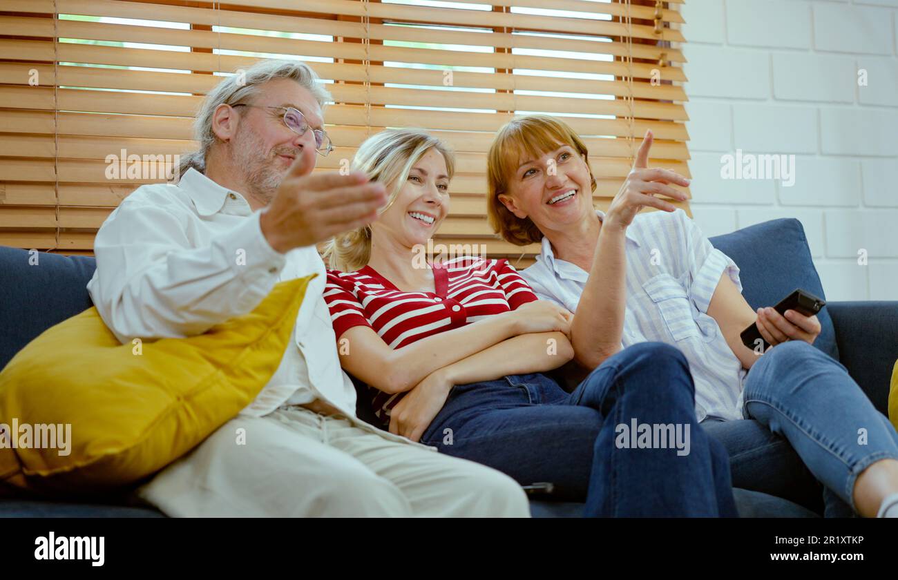 Glückliche Familie, die auf dem Sofa sitzt und zu Hause fernsieht. Stockfoto