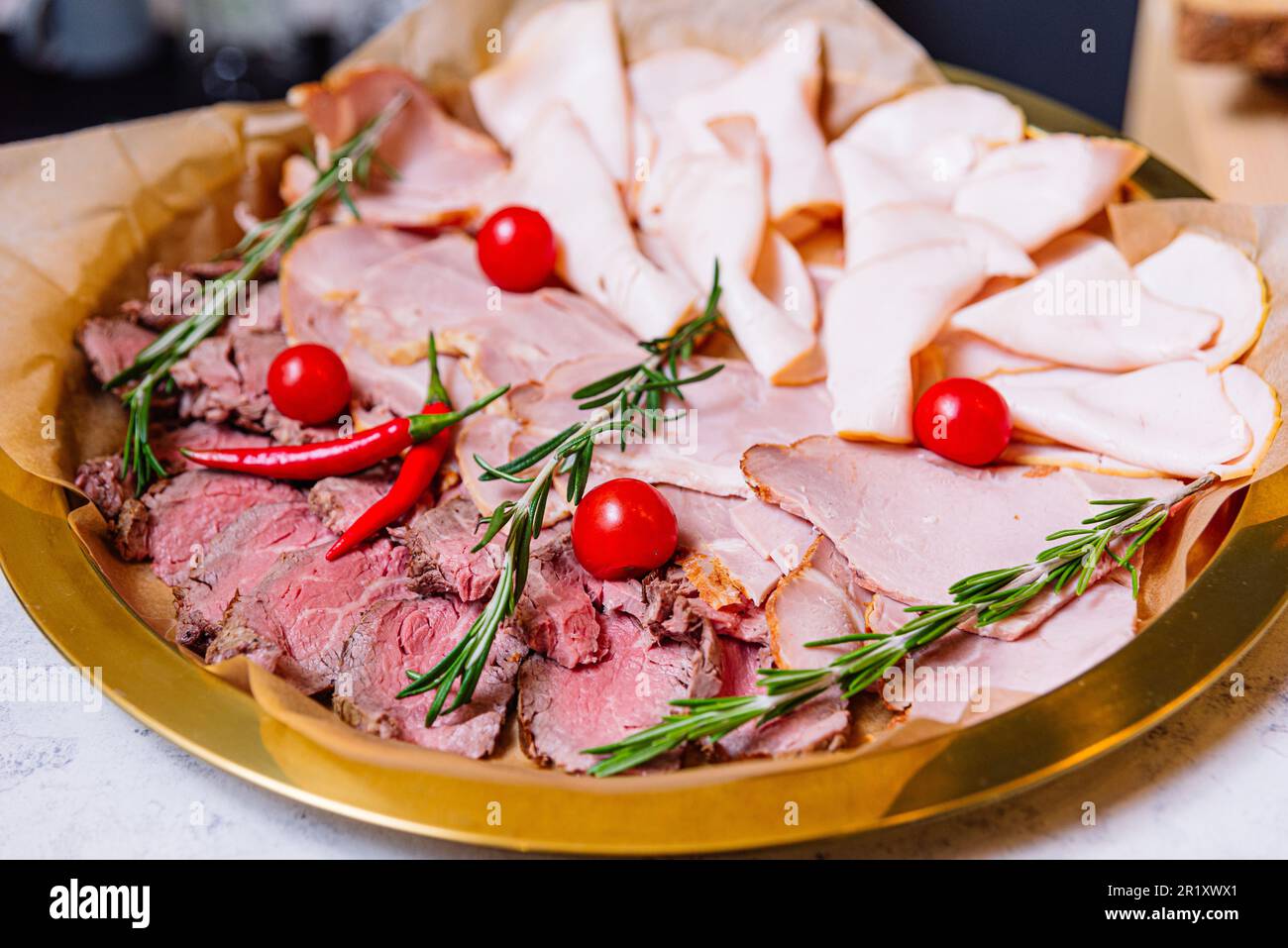 Eine köstliche Auswahl an dünnen Fleischscheiben, einschließlich Rind- und Schweinewürsten, Schinken und roter Paprika mit Rosmarin. Begleitet von frischer kirschtomate Stockfoto