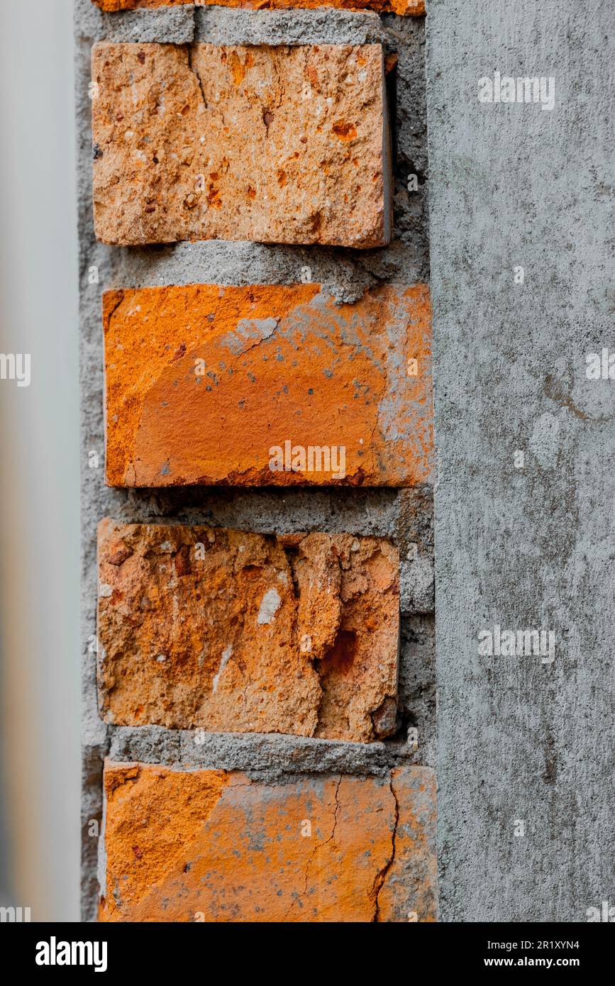 Die Nahaufnahme riss eine alte Ziegelsteinmauer aus Beton. Stockfoto