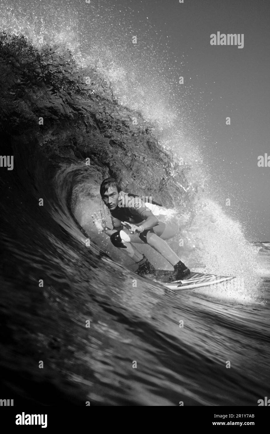 U-Bahn-Fahrt vom Wasser aus fotografiert. Die brechende Welle umrahmt die Surferin Carwyn Williams perfekt in Position mit einer Hand in Friedenszeichen Stockfoto