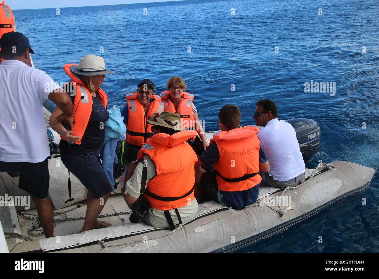 Rettungsboot aus Gummi mit Passagieren in orangefarbenen Rettungswesten Stockfoto