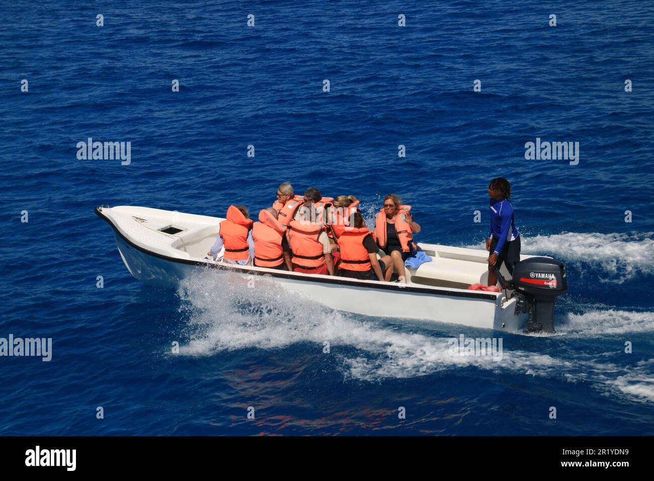 Rettungsboot aus Gummi mit Passagieren in orangefarbenen Rettungswesten Stockfoto