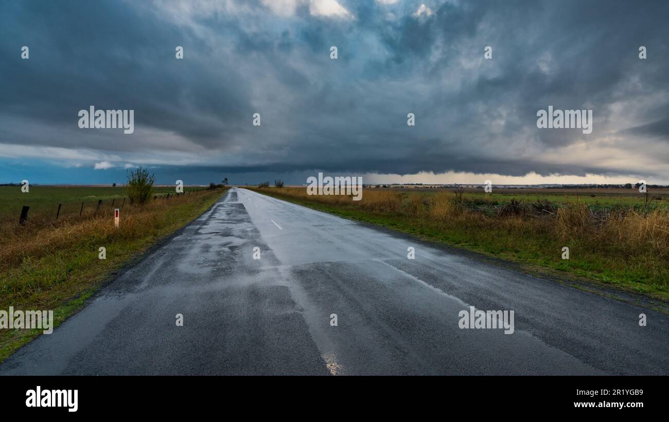 Blick auf eine nasse Landstraße in Richtung Sturmfront am Moolort in Central Victoria, Australien Stockfoto