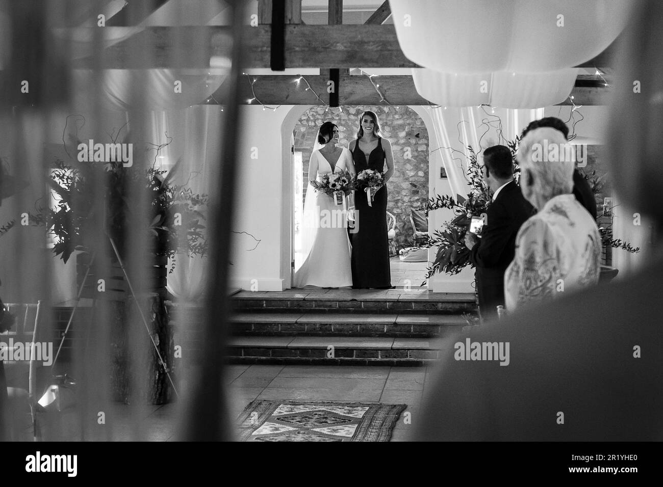 Hochzeitstag, Braut verbindet Arme mit Schwester, während sie an ihrem Hochzeitstag zum Altar gingen, Braut/Schwester schaut auf ihre Trauzeugin Stockfoto