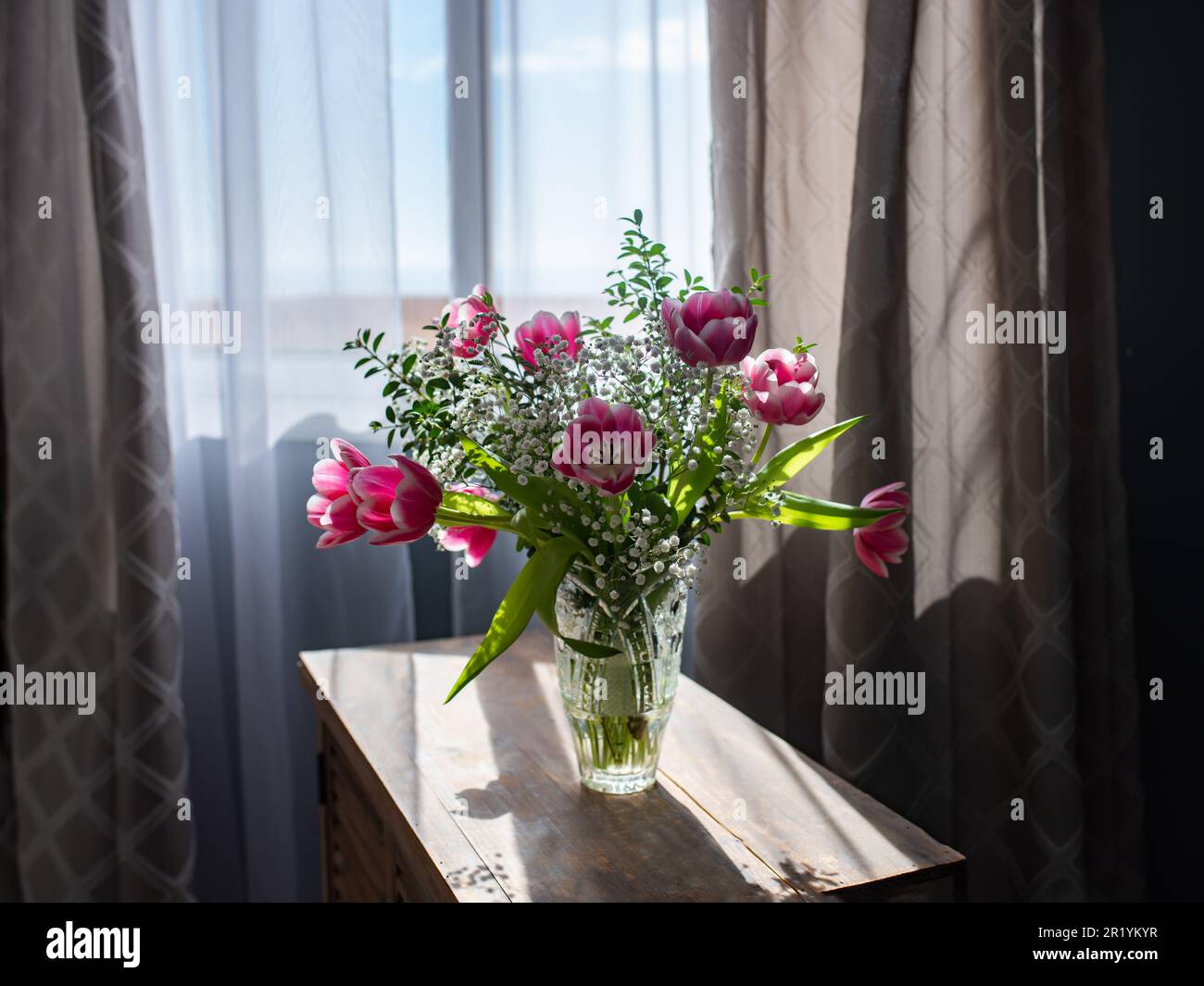 Wunderschöner Strauß von Tulpen in Glasvase auf weißem Marmortisch. Platz für Text. Stockfoto