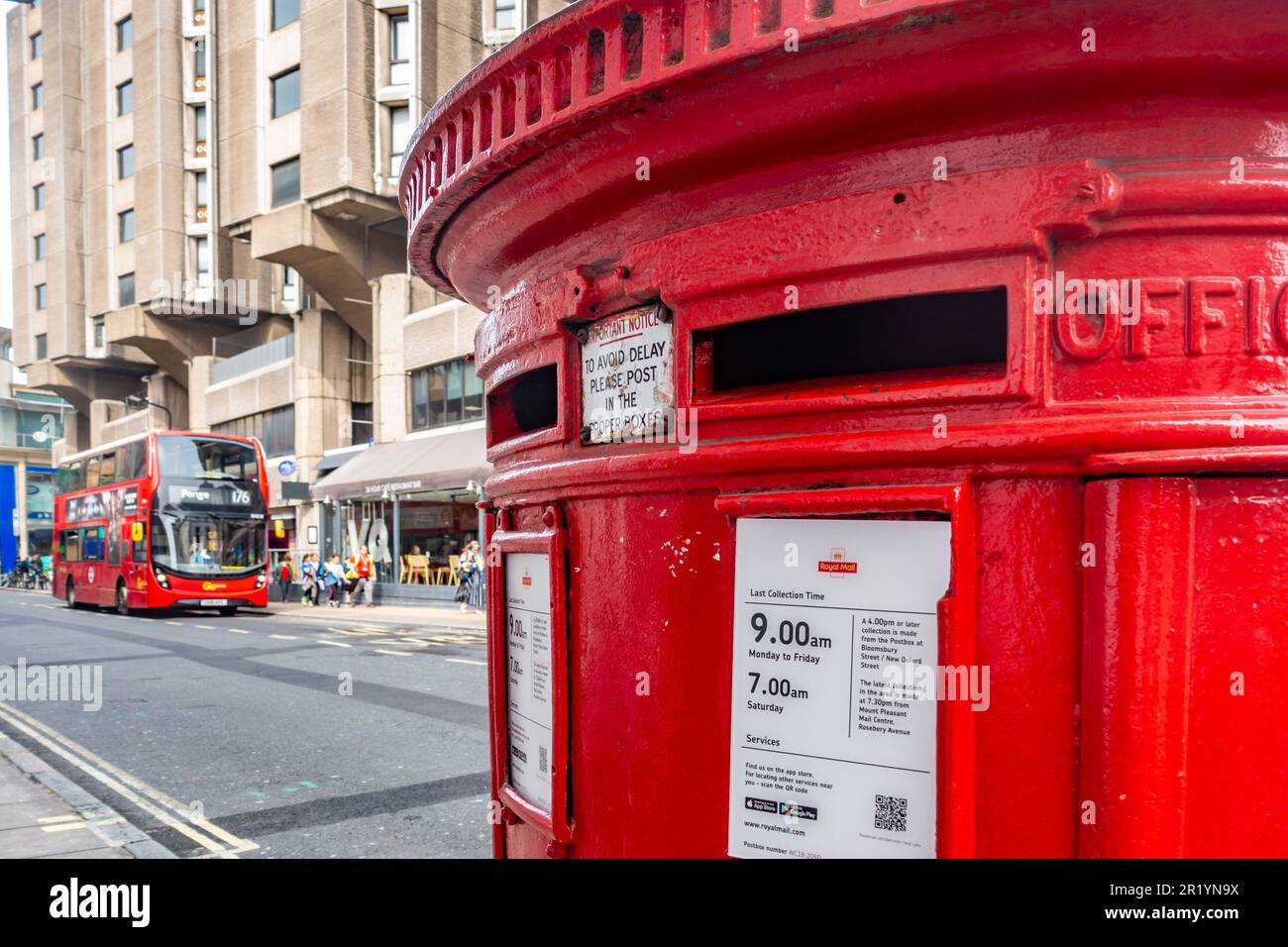 Ein rotes Postfach von Royal Mail im Vordergrund und ein roter Doppeldeckerbus im Hintergrund auf der Great Russel Street in London, Großbritannien Stockfoto