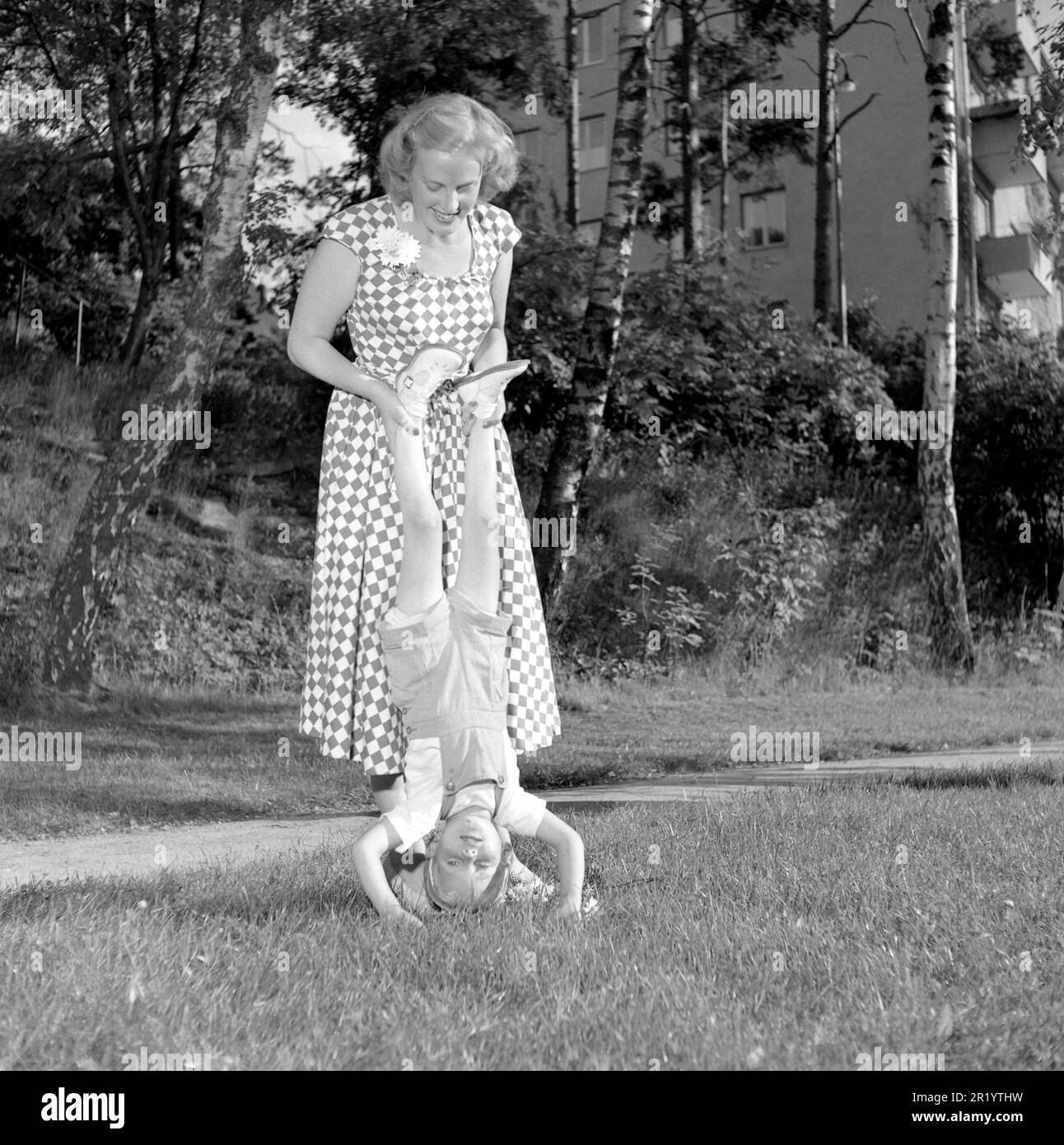 Spaß in den 1950er Jahren. Eine Mutter spielt draußen mit ihrem Kind und hilft ihm dabei, das Gleichgewicht zwischen Händen und Kopf zu halten. Schweden 5. juli 1952. Conard Ref. 2066 Stockfoto