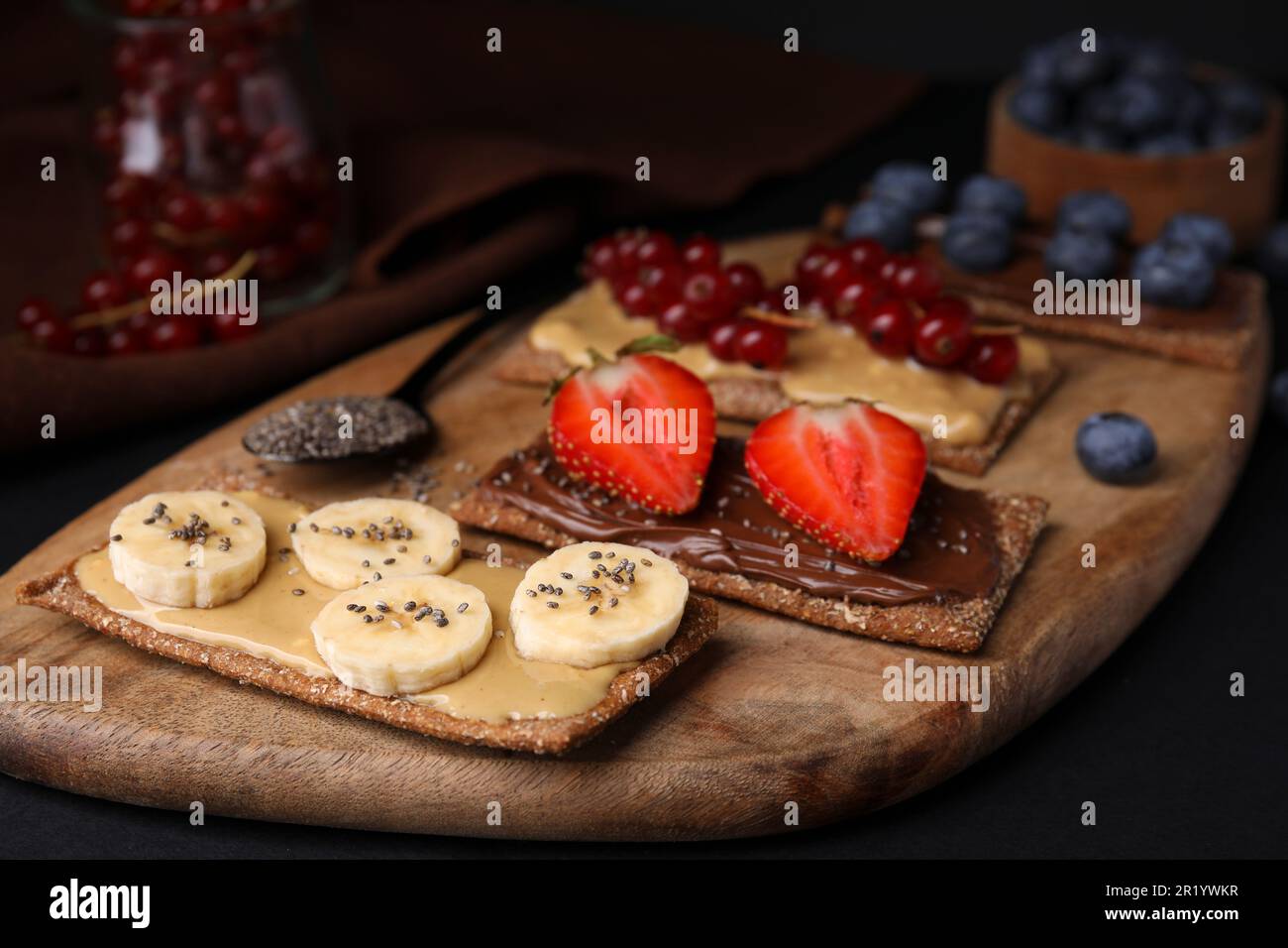 Frisches knuspriges Roggen-Knusperbrot mit verschiedenen Belägen auf schwarzem Tisch, Nahaufnahme Stockfoto