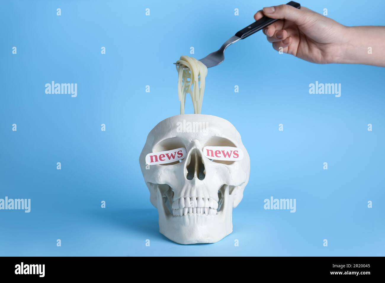 Das Konzept der Informationskampfführung. Eine Frau, die Nudeln aus dem menschlichen Schädel nimmt, Nahaufnahme. Einfluss von Mediennachrichten Stockfoto