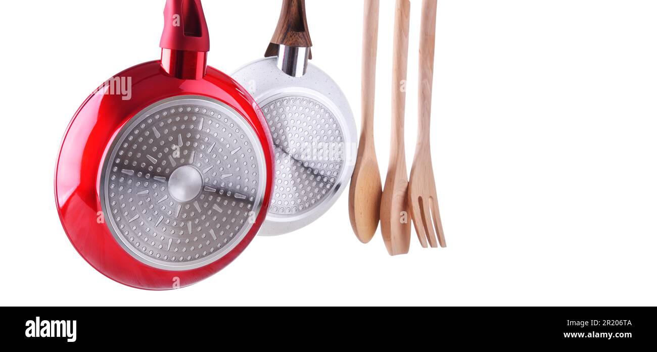 Zwei hängende Bratpfannen und Küchenutensilien isoliert auf Weiß Stockfoto