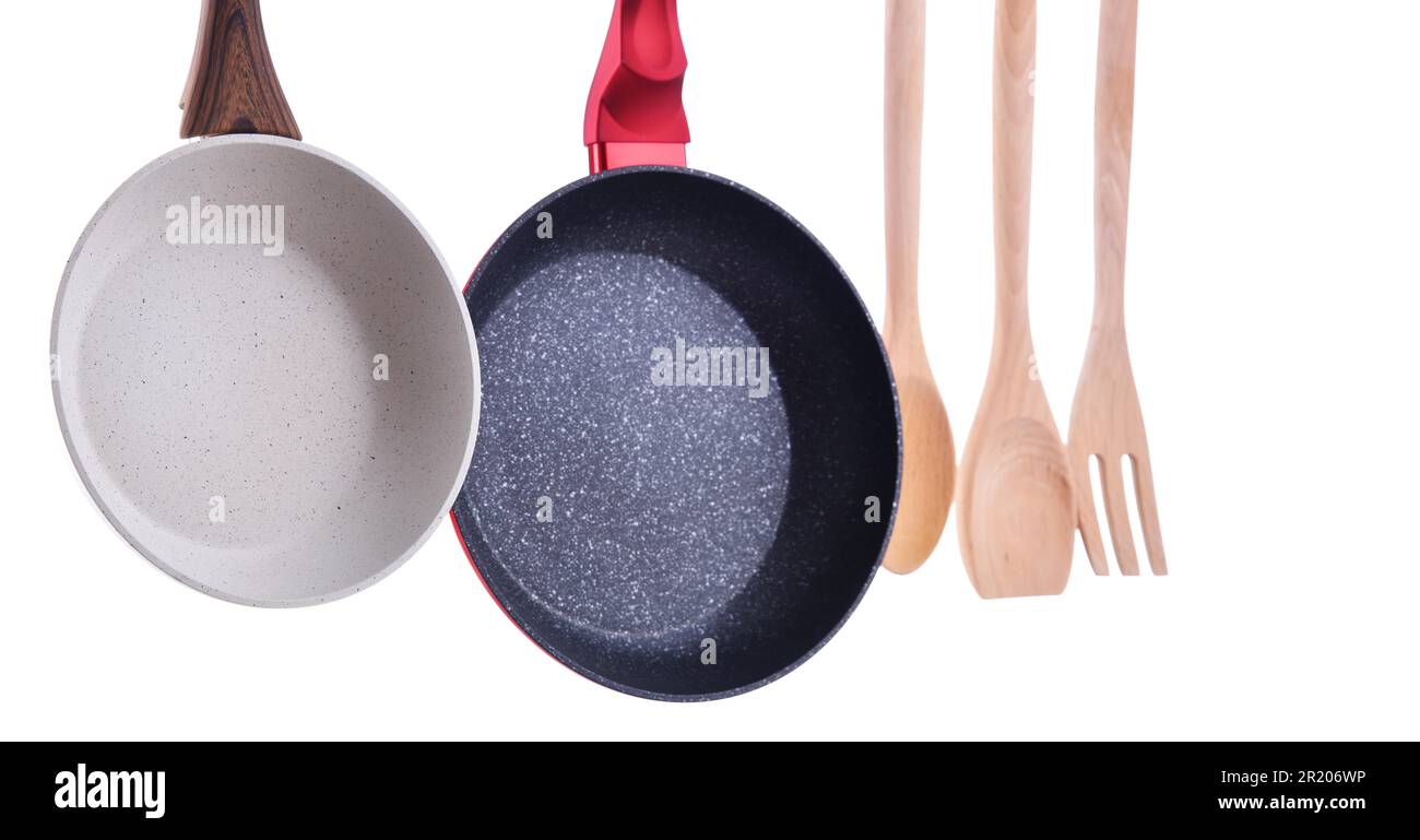 Zwei hängende Bratpfannen und Küchenutensilien isoliert auf Weiß Stockfoto