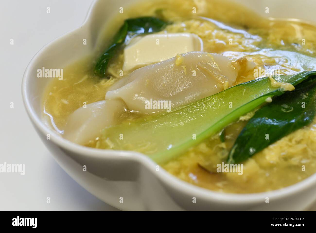 Chinesische Eiersuppe mit Teigtaschen, Tofu und Kohlgemüse Stockfoto