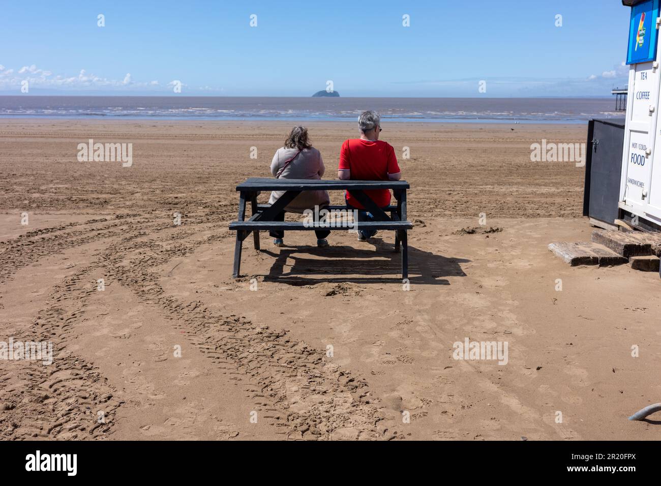 Das Paar saß auf einer Bank mit Blick auf das Meer in der Weston Super Stute Stockfoto