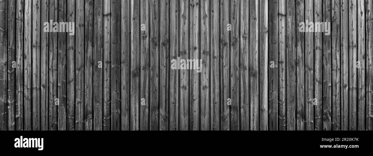 Dunkelgraue Holzwand aus vertikalen Brettern mit intensiver Holzmaserung Stockfoto