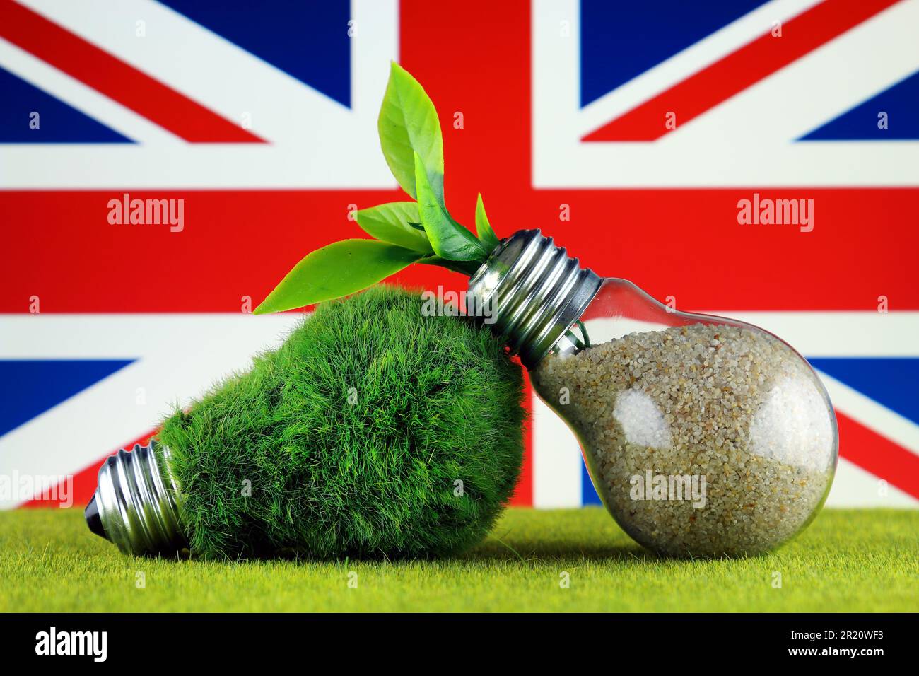 Grüne Öko-Glühbirne mit Gras, Pflanzen, die in der Glühbirne wachsen, und Flagge des Vereinigten Königreichs. Erneuerbare Energien. Strompreise, Energieeinsparung in Stockfoto