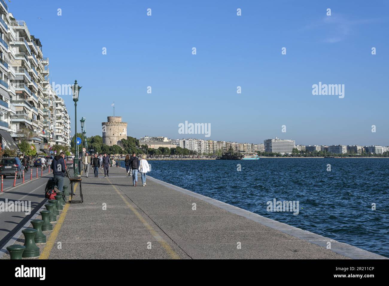 Thessaloniki, Griechenland, 28. April 2023: Strandpromenade am Mittelmeer mit Spaziergängern zum Weißen Turm, dem berühmten Wahrzeichen und Stockfoto