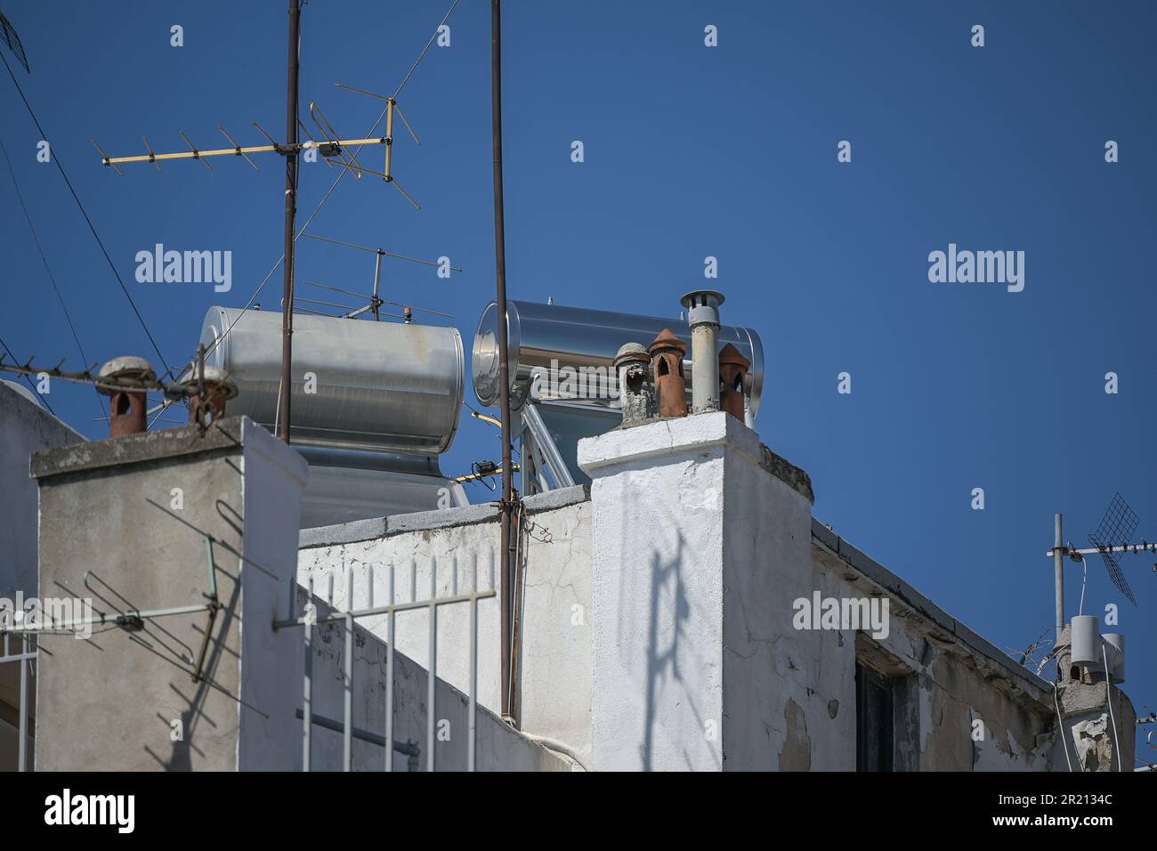 Thermosiphonsysteme mit Sonnenkollektor und Wassertank auf dem Dach eines hohen Wohnungsgebäudes, alternative Energie durch Sonne und passive Wärmetauscher Stockfoto