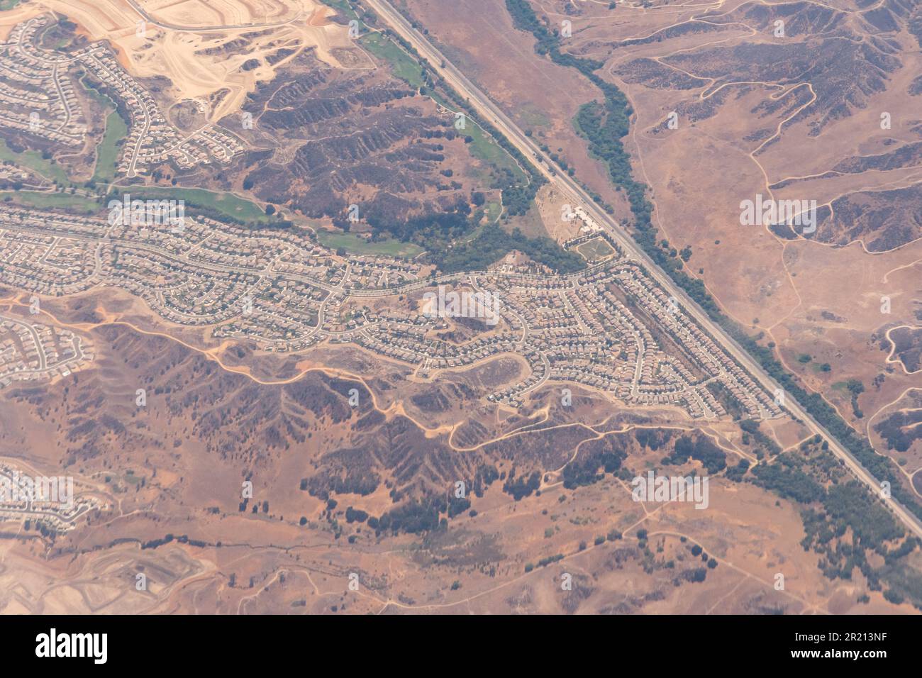 Blick aus der Vogelperspektive auf eingezäunte Gemeinden, Bauvorhaben, Autobahnen und Unterteilungen in der Wüste außerhalb von Los Angeles in Südkalifornien Stockfoto