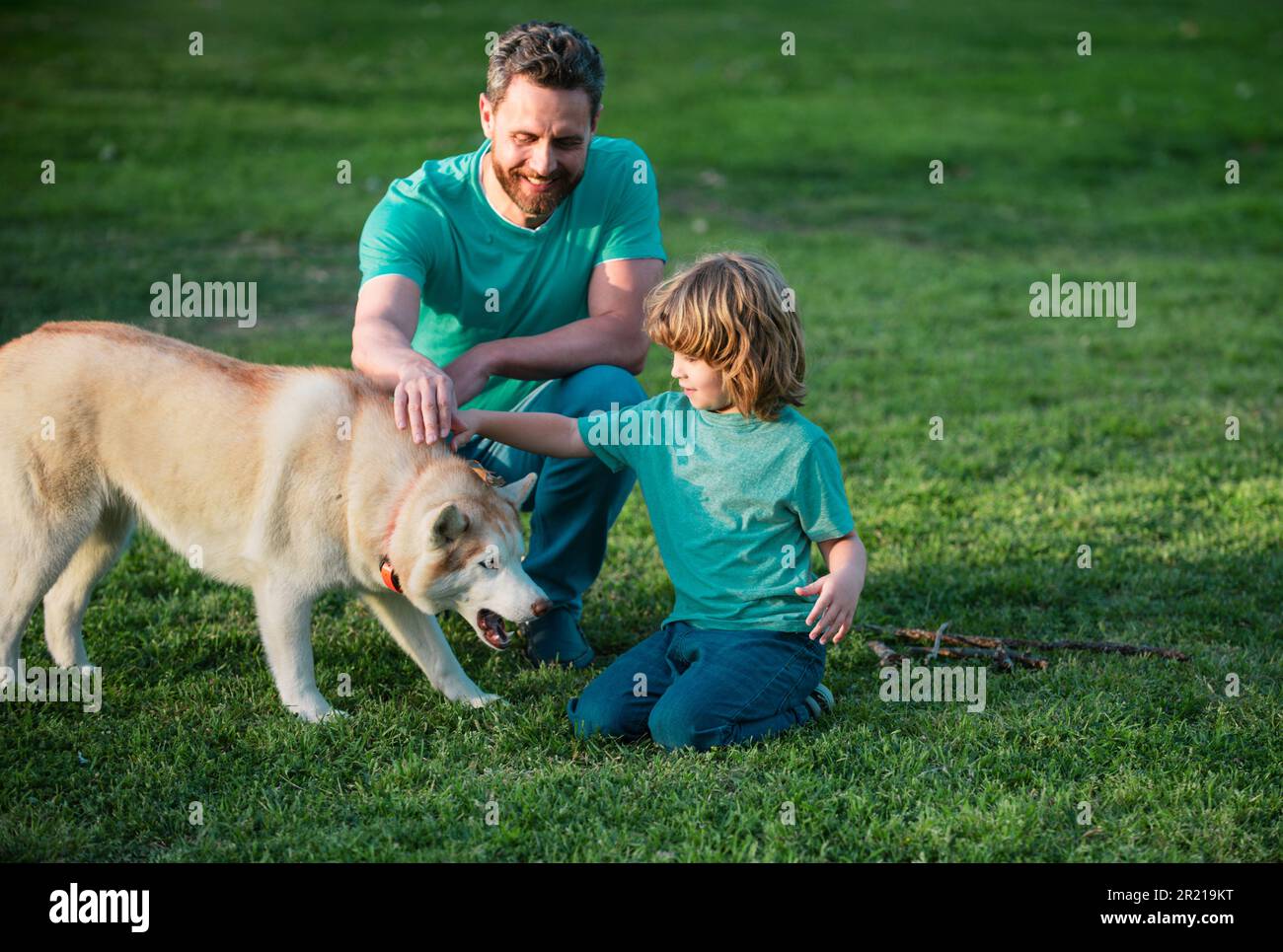 Vater und Sohn spielen mit Hund im Garten. Papa und Kind mit Haustier, die  Spaß im Freien haben Stockfotografie - Alamy