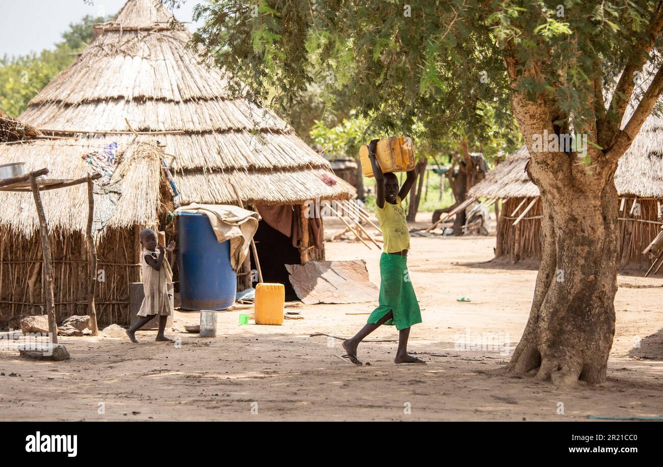 Torit, Südsudan - 18. August 2021: Nicht identifizierte Kinder transportieren Wasser und machen Hausarbeiten in einem Dorf im ländlichen Südsudan. Stockfoto