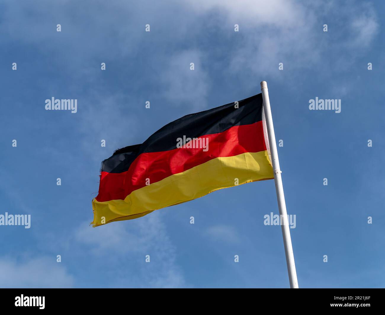 Eine deutsche Flagge auf einem Fahnenmast vor einem blauen Himmel. Stockfoto