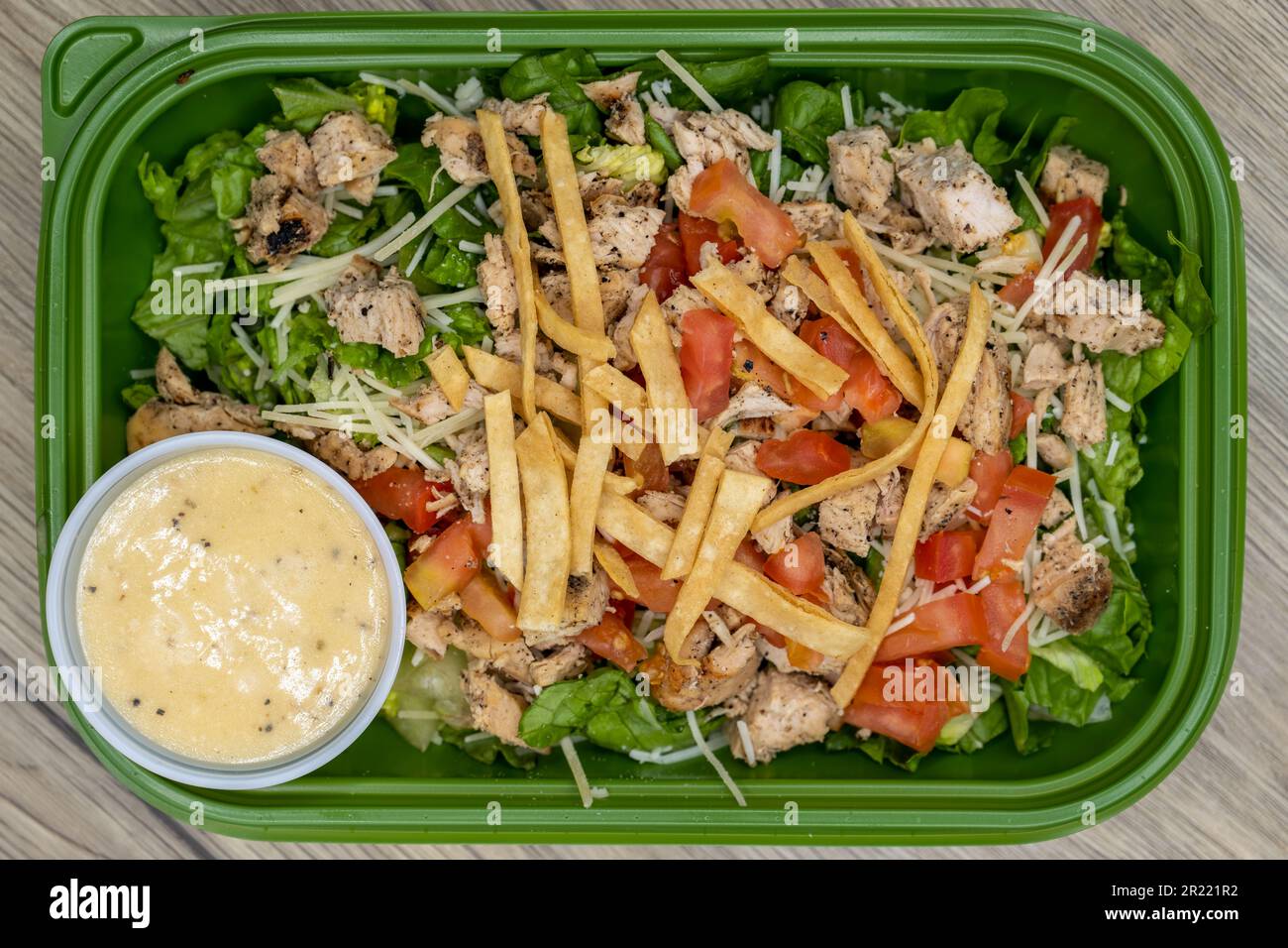 Blick von oben auf die Bestellung von Caesar Salat wird frisch in einem Kunststoffbehälter mit Dressing an der Seite zubereitet. Stockfoto