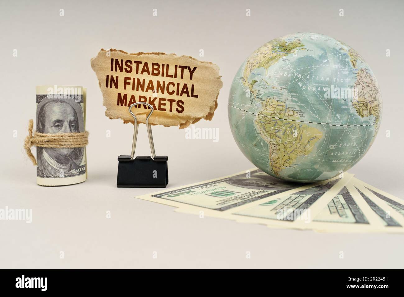 Geschäfts- und Finanzkonzept. Auf dem Tisch liegen Dollar, ein Globus und ein Schild mit der Inschrift - Instabilität auf den Finanzmärkten Stockfoto