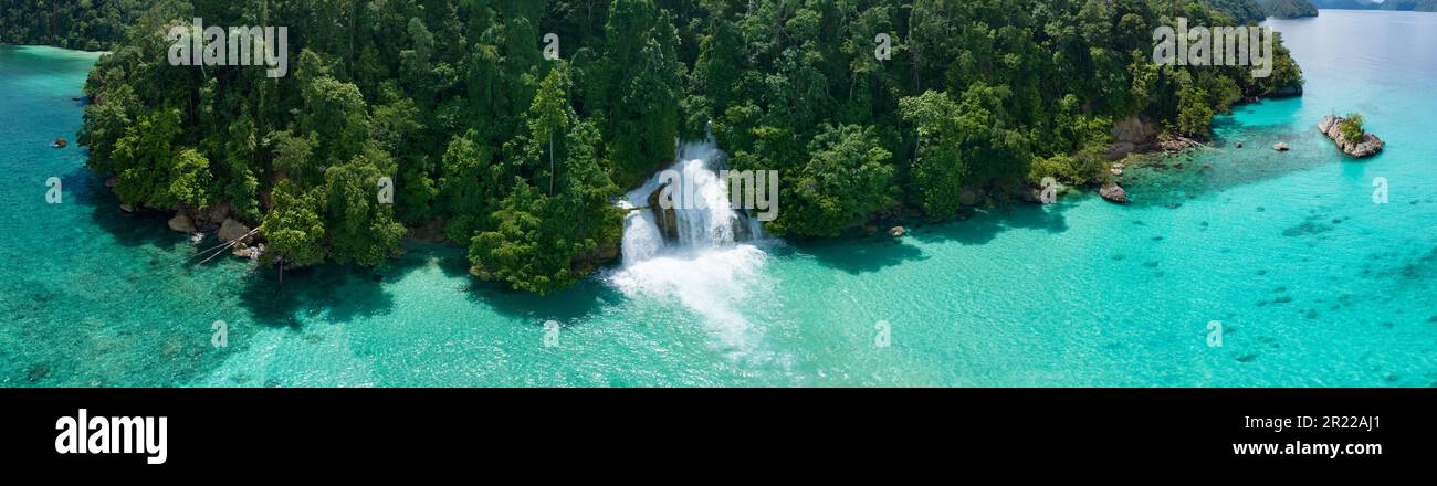 Ein Wasserfall stürzt aus dem Regenwald in den Ozean an der Küste von West Papua, Indonesien. Dieses Gebiet in der Nähe von Momon verfügt über eine hohe Artenvielfalt. Stockfoto