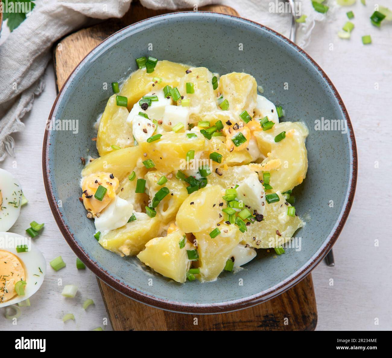 Salat aus Kartoffeln, Eiern, grünen Zwiebeln und Mayonnaise auf einem Teller auf weißem Hintergrund, Draufsicht. Stockfoto