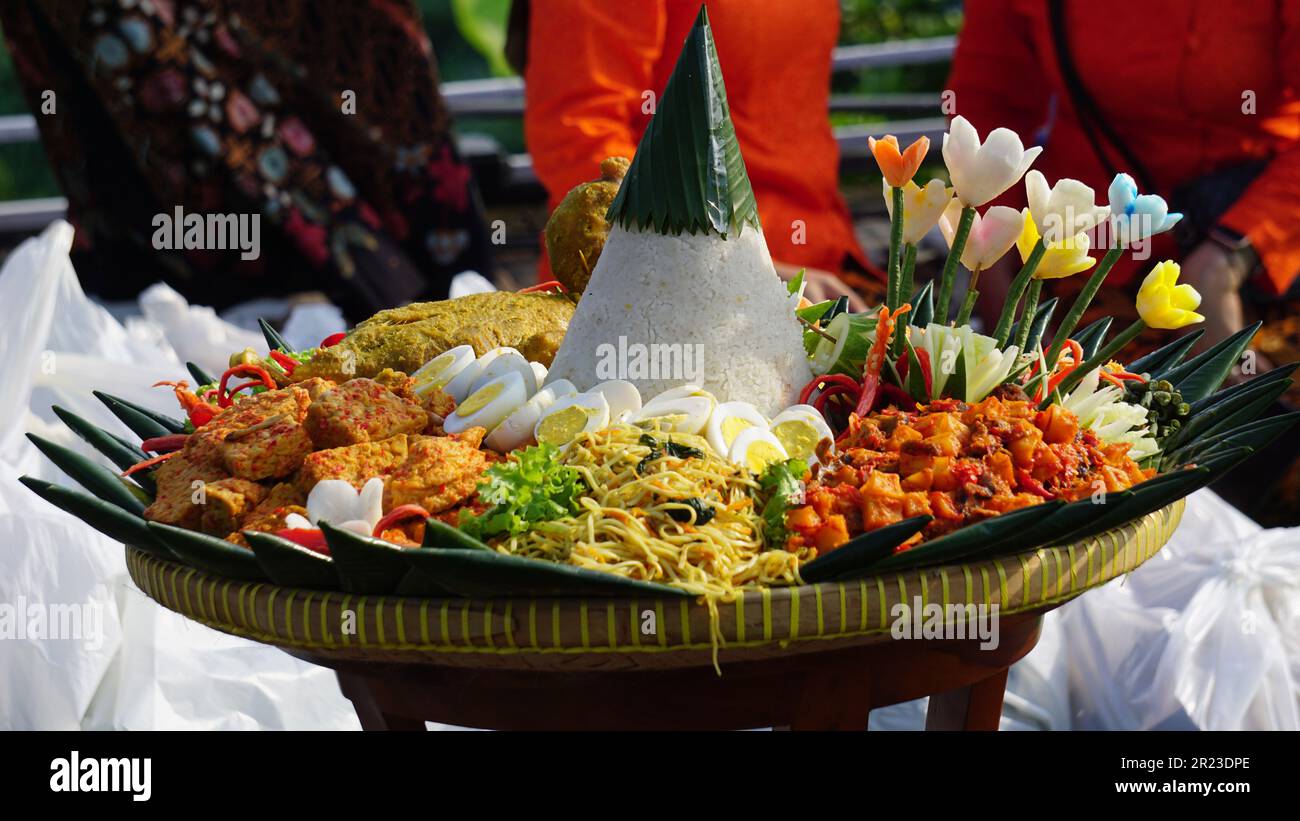 Nasi Tumpeng (Konusreis) serviert mit Urap-Uap (indonesischer Salat), gebratenem Hähnchen und Nudeln. Nasi-Tumpeng wird normalerweise auf Geburtstagspartys serviert Stockfoto