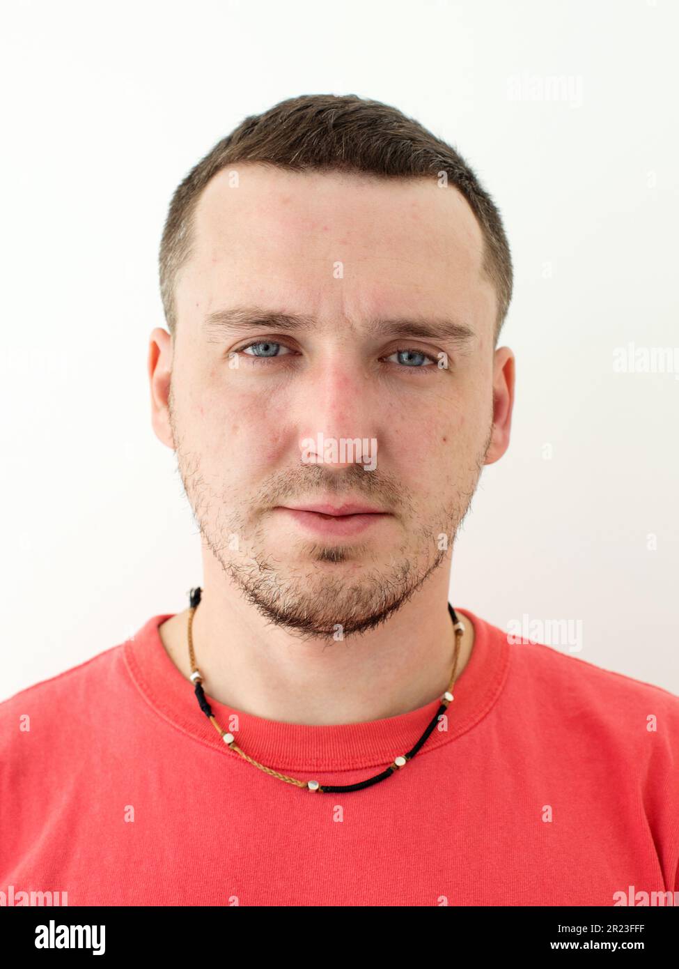Passfoto eines Mannes in rotem T-Shirt mit Kette Stockfoto