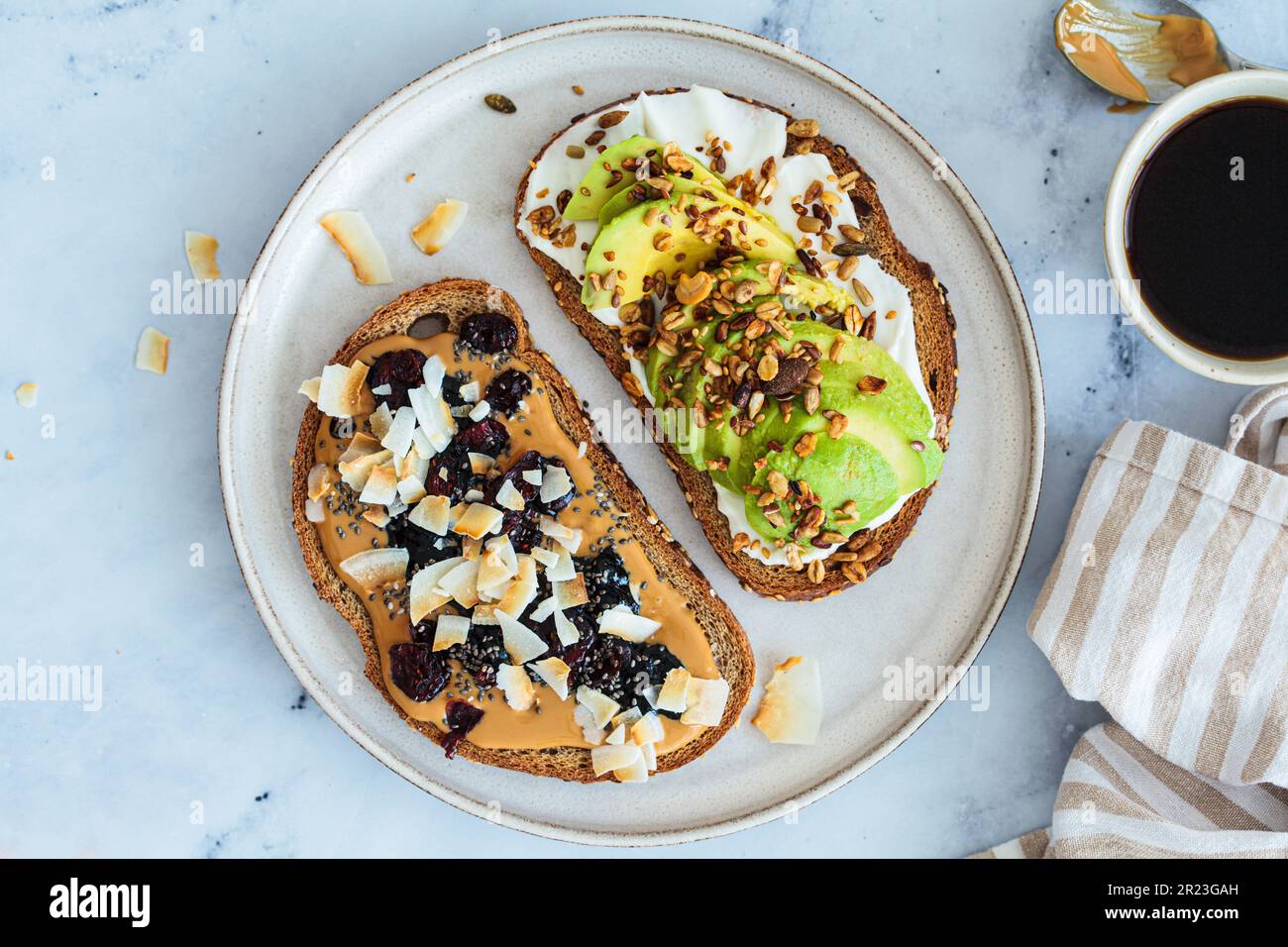 Vegane Frühstückstoasts mit Avocado und Erdnussbutter auf weißem Marmorhintergrund, Blick von oben. Stockfoto