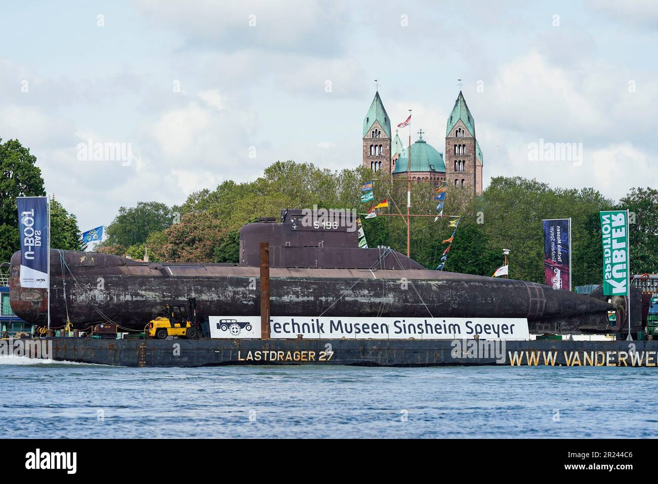 Speyer, Deutschland. 17. Mai 2023. Ein stillgelegtes U-Boot U17 segelt auf dem Rhein vor den Türmen der Kathedrale von Speyer auf einem Transportschiff zum natürlichen Hafen von Speyer. Das Boot war seit über 35 Jahren bei der deutschen Marine in Betrieb und soll am 21. Mai auf der Straße zum Speyer Museum of Technology transportiert werden. Kredit: Uwe Anspach/dpa/Alamy Live News Stockfoto