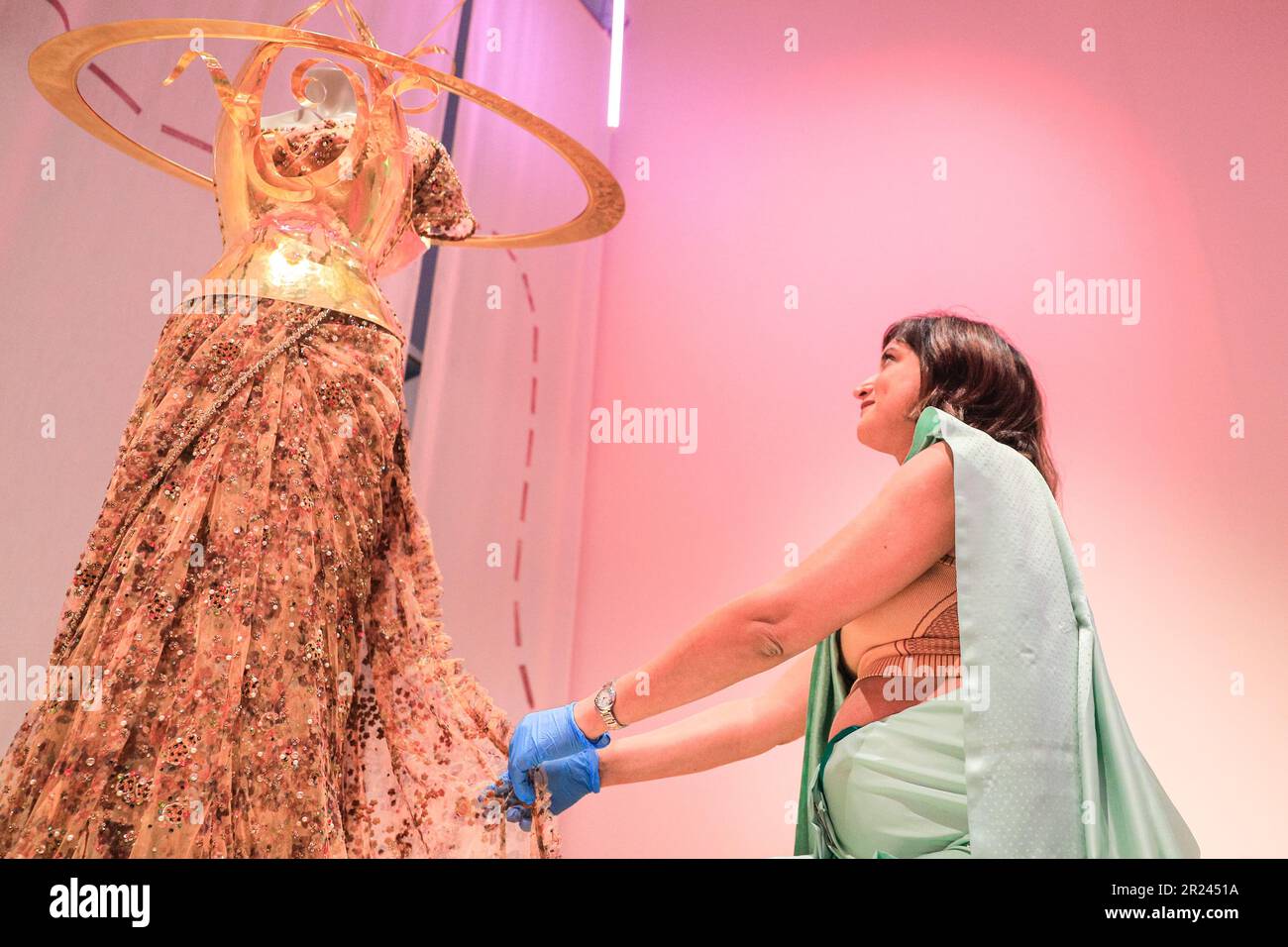 London, Großbritannien. 17. Mai 2023. Priya Khanchandani (Kurator) des Design Museums stellt das Herzstück ein, ein wunderschönes goldenes Sabyasachi-Design, das Sari 2022 zum ersten Mal zur Met Gala getragen hat. „The Offbeat Sari“ ist die erste große britische Ausstellung über den zeitgenössischen Sari, mit 60 atemberaubenden Saris auf der Disla im Design Museum, Kensington. Die Ausstellungen werden vom 19. Mai bis 17. September 2023 ausgestellt. Kredit: Imageplotter/EMPICS/Alamy Live News Stockfoto