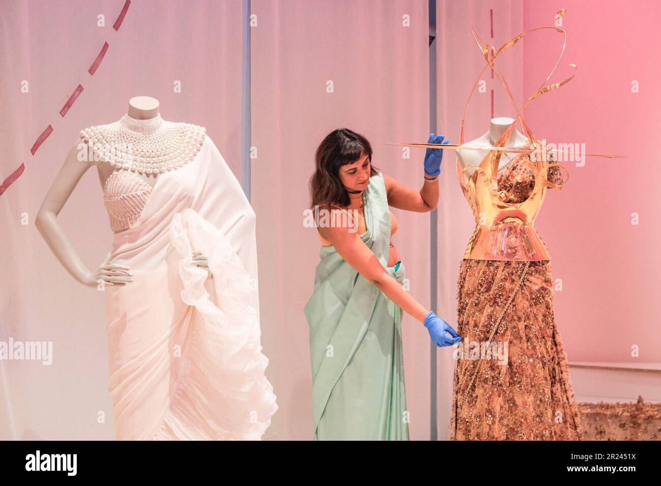 London, Großbritannien. 17. Mai 2023. Priya Khanchandani (Kurator) des Design Museums stellt das Herzstück ein, ein wunderschönes goldenes Sabyasachi-Design, das Sari 2022 zum ersten Mal zur Met Gala getragen hat. „The Offbeat Sari“ ist die erste große britische Ausstellung über den zeitgenössischen Sari, mit 60 atemberaubenden Saris auf der Disla im Design Museum, Kensington. Die Ausstellungen werden vom 19. Mai bis 17. September 2023 ausgestellt. Kredit: Imageplotter/EMPICS/Alamy Live News Stockfoto